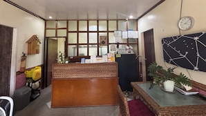 A reception area with a wooden reception desk, a clock, and a wall-mounted bulletin board. - Shat'S Guesthouse Siargao Near Beach (General Luna)