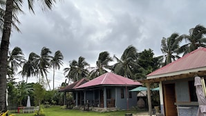 A house with a red roof, a small porch, and a grassy yard. - Shat'S Guesthouse Siargao Near Beach (General Luna)