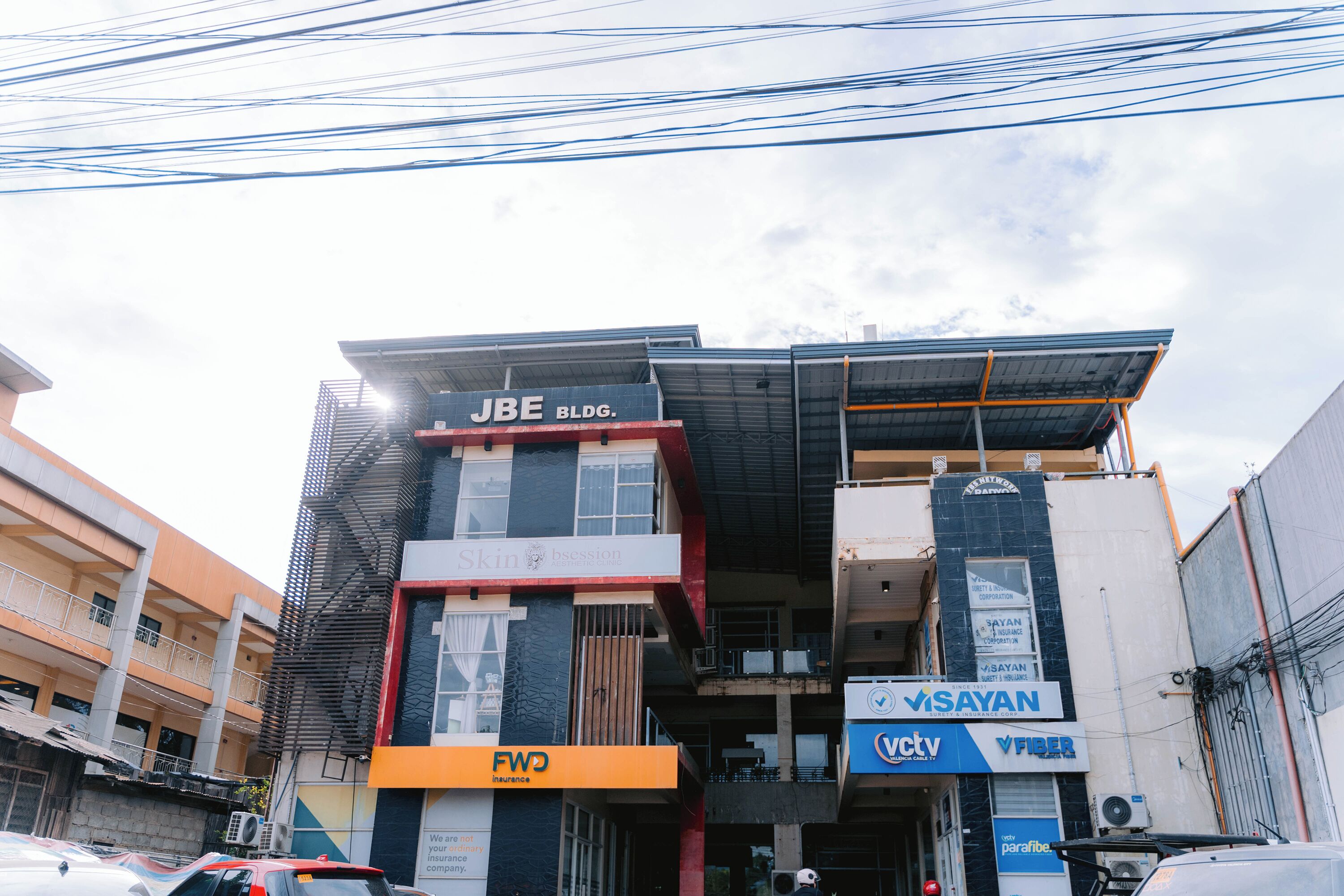 A multi-story building with commercial signage, including 'JBE BLDG.' and 'VISAYAN.'