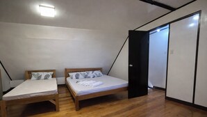 A room with two wooden beds, a black wardrobe, and a sloped ceiling. - Angelito's Beach House Siargao near Beach (General Luna)