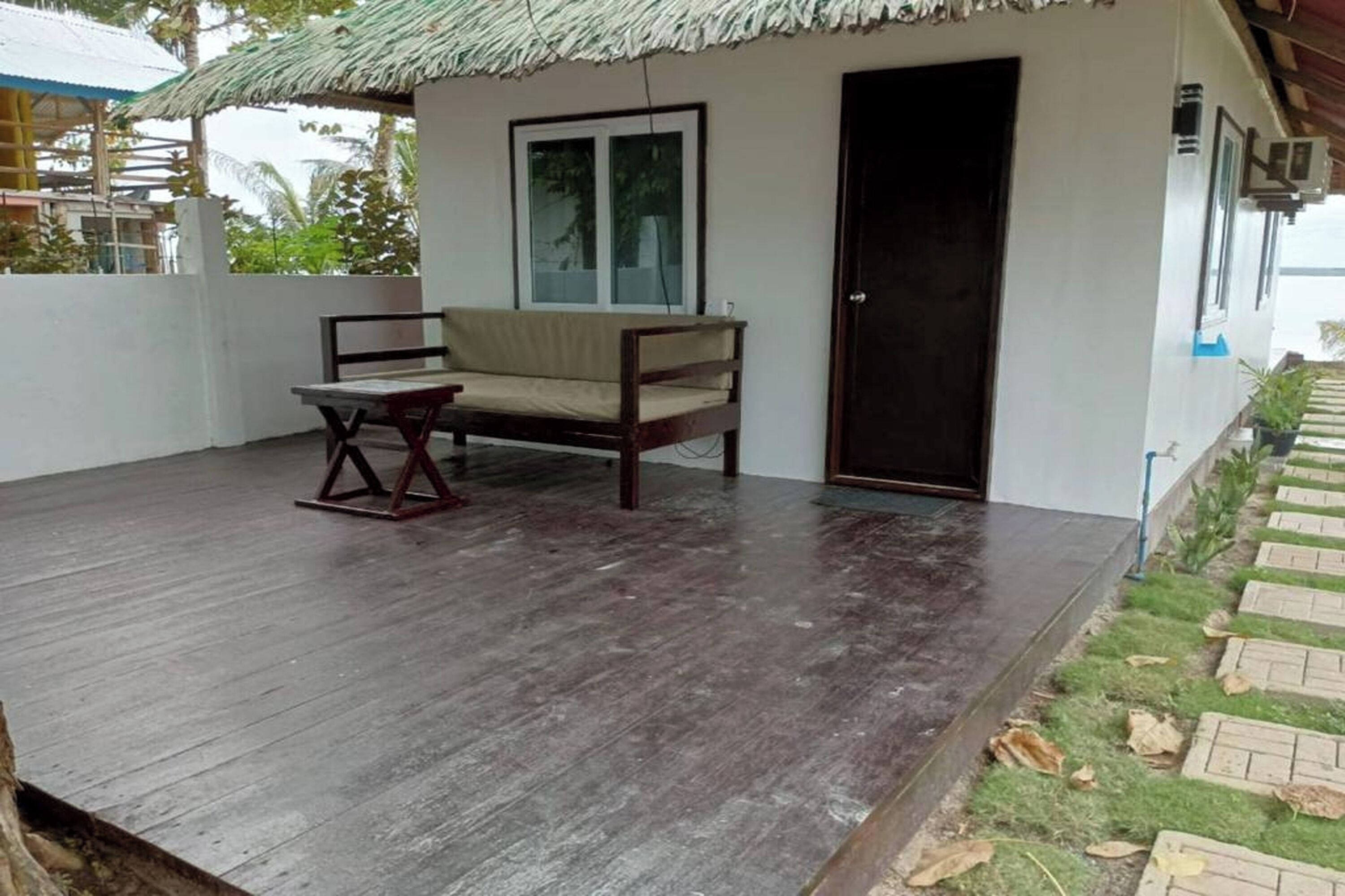 A wooden deck with a sofa and table, a door, and a window.