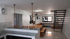 A modern kitchen with a central island, dining area with benches, and a staircase with a railing. - Angelito's Beach House Siargao near Beach (General Luna)