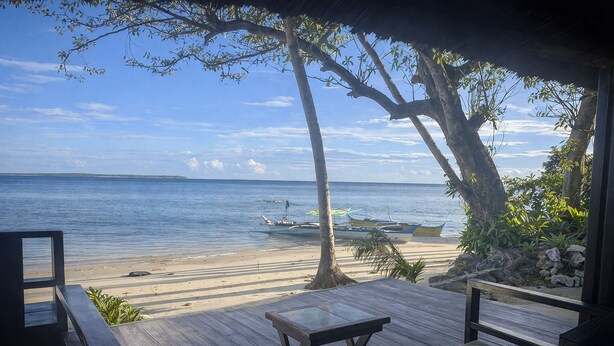 A wooden deck with a view of the beach and boats. - Angelito's Beach House Siargao near Beach (General Luna)