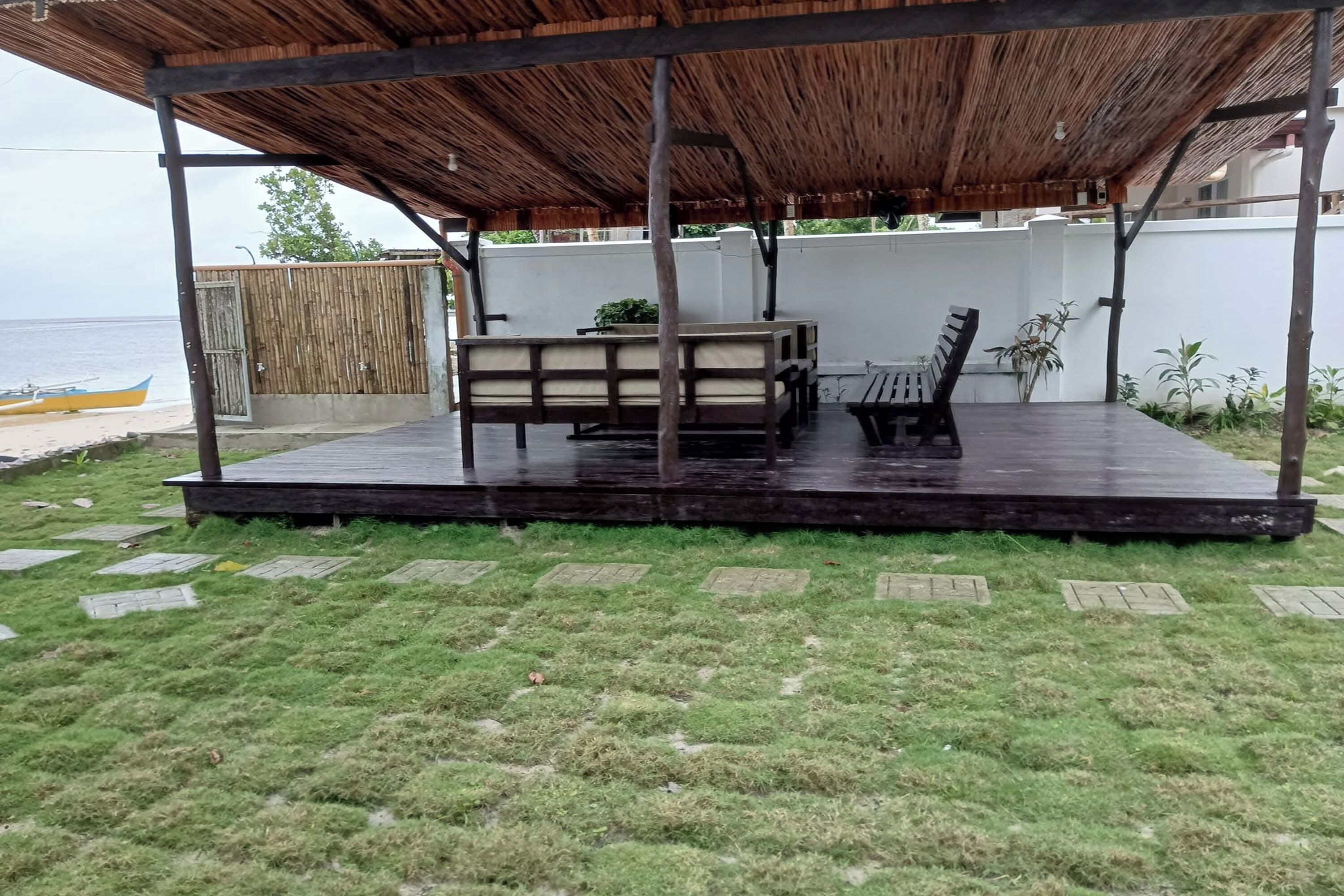 A covered outdoor seating area with a table and chairs, a wooden deck, and a view of the beach.