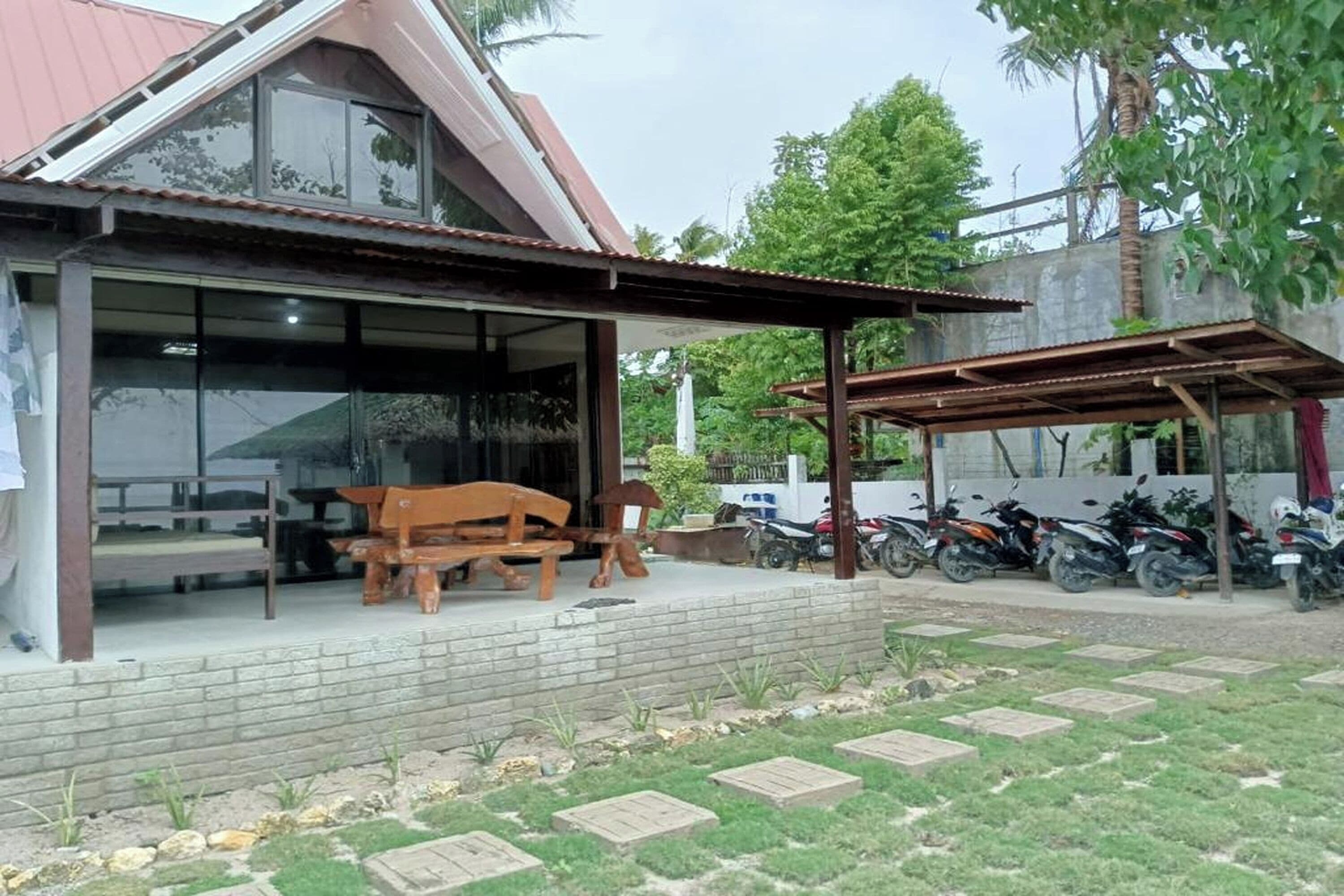 A house with a covered porch, a bench, and a motorcycle parked outside.