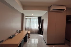 Habitación de hotel con un escritorio alargado, una banca y un armario.