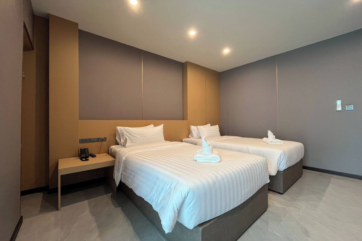 Une chambre d’hôtel avec deux lits, une table de chevet et une station de recharge fixée au mur.