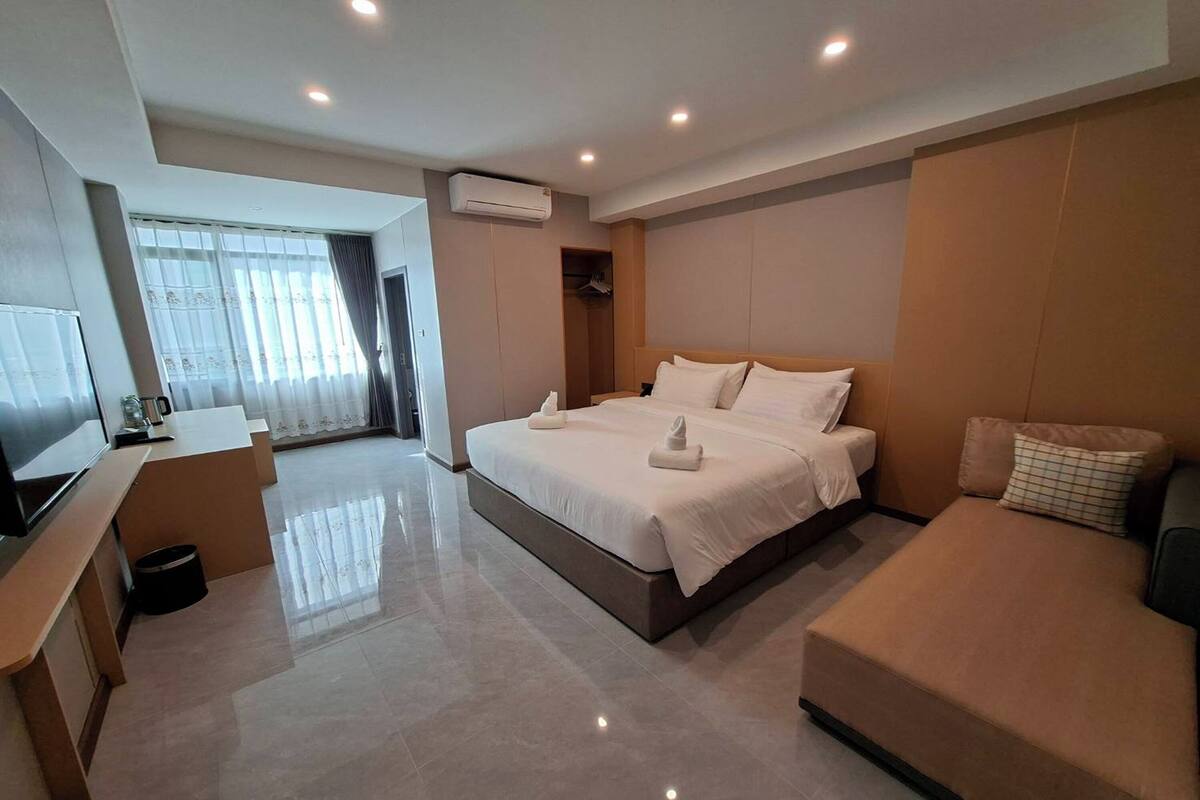 Une chambre d’hôtel moderne dotée d’un grand lit, d’un canapé, d’une télévision et d’un dressing.