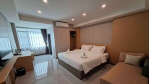 Una habitación de hotel moderna con una cama grande, un sofá, un televisor y un vestidor.