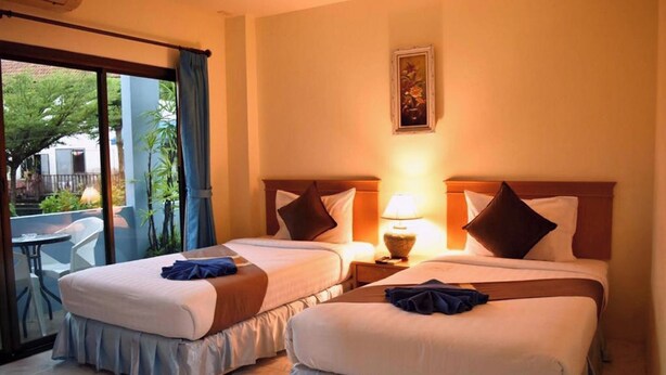Une chambre d’hôtel avec deux lits, un balcon et un coin repas.