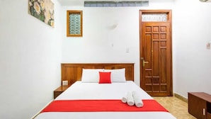 A hotel room with a large bed, a wooden headboard, a red throw, and a set of towels on the bed. - Collection O Long Phung Hotel (Ho Chi Minh City)