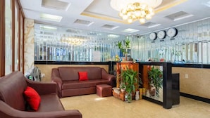 A modern lobby with a brown leather sofa, a reception desk, and a chandelier. - Collection O Long Phung Hotel (Ho Chi Minh City)