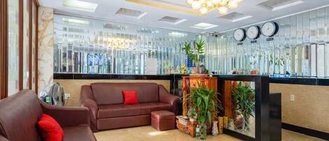 A modern lobby with a brown leather sofa, a reception desk, and a chandelier.