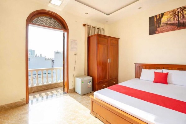 Habitación de hotel con cama, armario y balcón con vista a la ciudad.