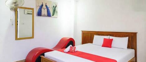 Ein Schlafzimmer mit einem Bett, einem roten Sessel, einem Spiegel und einem Bild an der Wand.