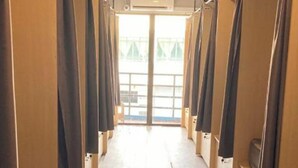 Un couloir avec des boxes individuels, une grande fenêtre au fond et une porte donnant sur l’extérieur.