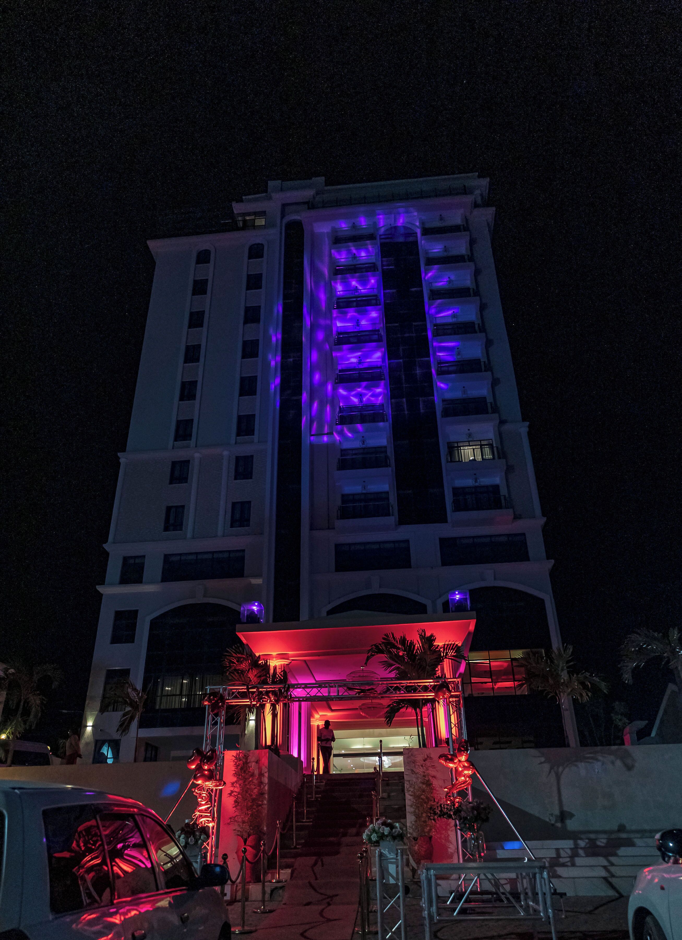 Un hotel de varios pisos con un atrio central, iluminado con luces moradas y rojas.