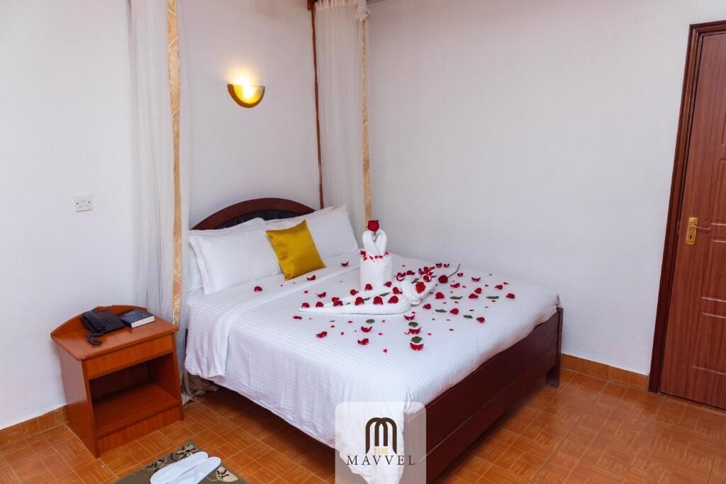 A neatly made bed with white linens, a wooden headboard, and a bedside table with a lamp.