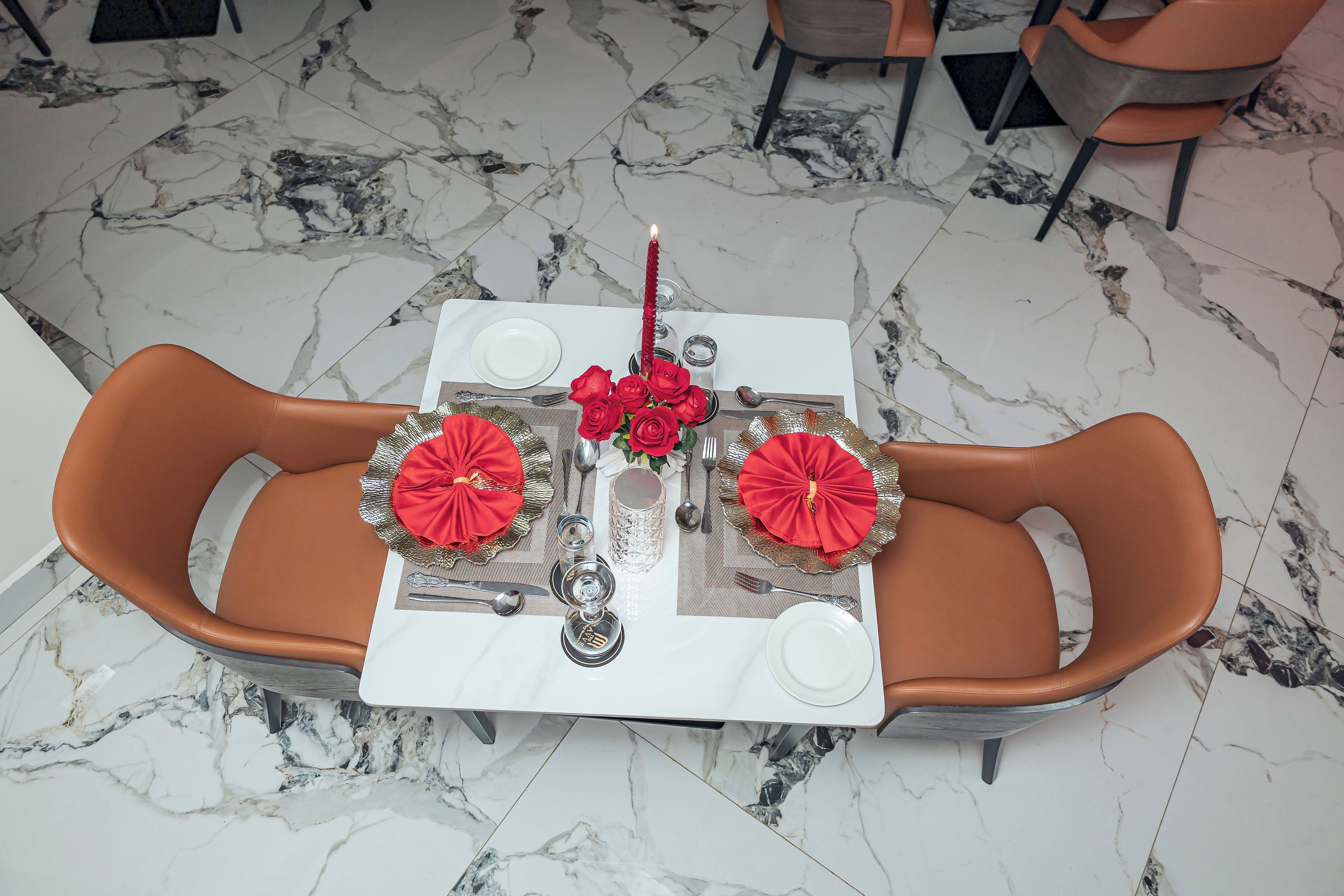 A dining table set with red tablecloths, two chairs, and a candle centerpiece.
