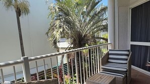 Un balcón con mobiliario de mimbre y vistas a palmeras.