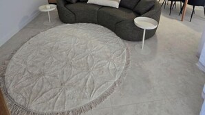 Una sala de estar con un sofá seccional gris, un tapete redondo, una mesa de comedor con sillas y un ventilador de techo.