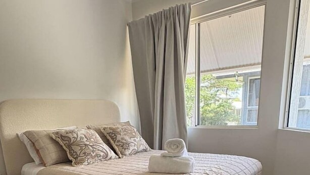 Un dormitorio con cama, cortinas y ventana.