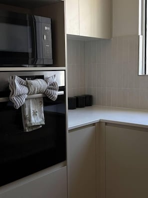 A kitchen with a microwave, oven, and a towel hanging on the oven door.