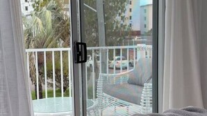 A bedroom with a bed, a sliding glass door leading to a balcony, and a view of a cityscape. - Walk to the beach - 3 Bed-2 carparks in North Ward (North Ward)