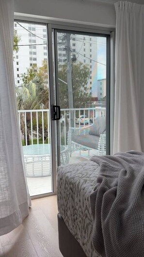 A bedroom with a bed, a sliding glass door leading to a balcony, and a view of a cityscape. - Walk to the beach - 3 Bed-2 carparks in North Ward (North Ward)
