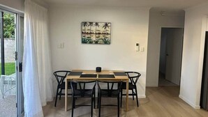 A dining area with a wooden table and black chairs, a painting on the wall, and a door leading to another room. - Walk to the beach - 3 Bed-2 carparks in North Ward (North Ward)