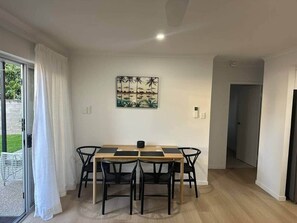 A dining area with a wooden table and black chairs, a painting on the wall, and a door leading to another room. - Walk to the beach - 3 Bed-2 carparks in North Ward (North Ward)