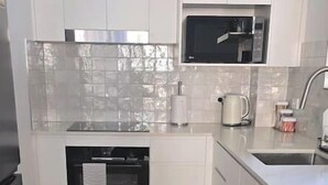 A kitchen with white cabinets, a microwave, a kettle, and a stainless steel refrigerator. - Walk to the beach - 3 Bed-2 carparks in North Ward (North Ward)