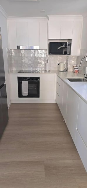 A kitchen with white cabinets, a microwave, a kettle, and a stainless steel refrigerator. - Walk to the beach - 3 Bed-2 carparks in North Ward (North Ward)