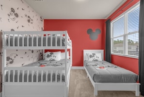 Ein Zimmer mit Etagenbetten, einer Mickey-Mouse-Wandsticker und einem Fenster mit Jalousien.