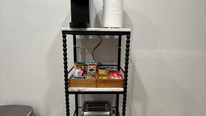 A kitchen counter with a coffee maker, paper towel holder, and a toaster. There are various food items and two bottles of water on the counter.