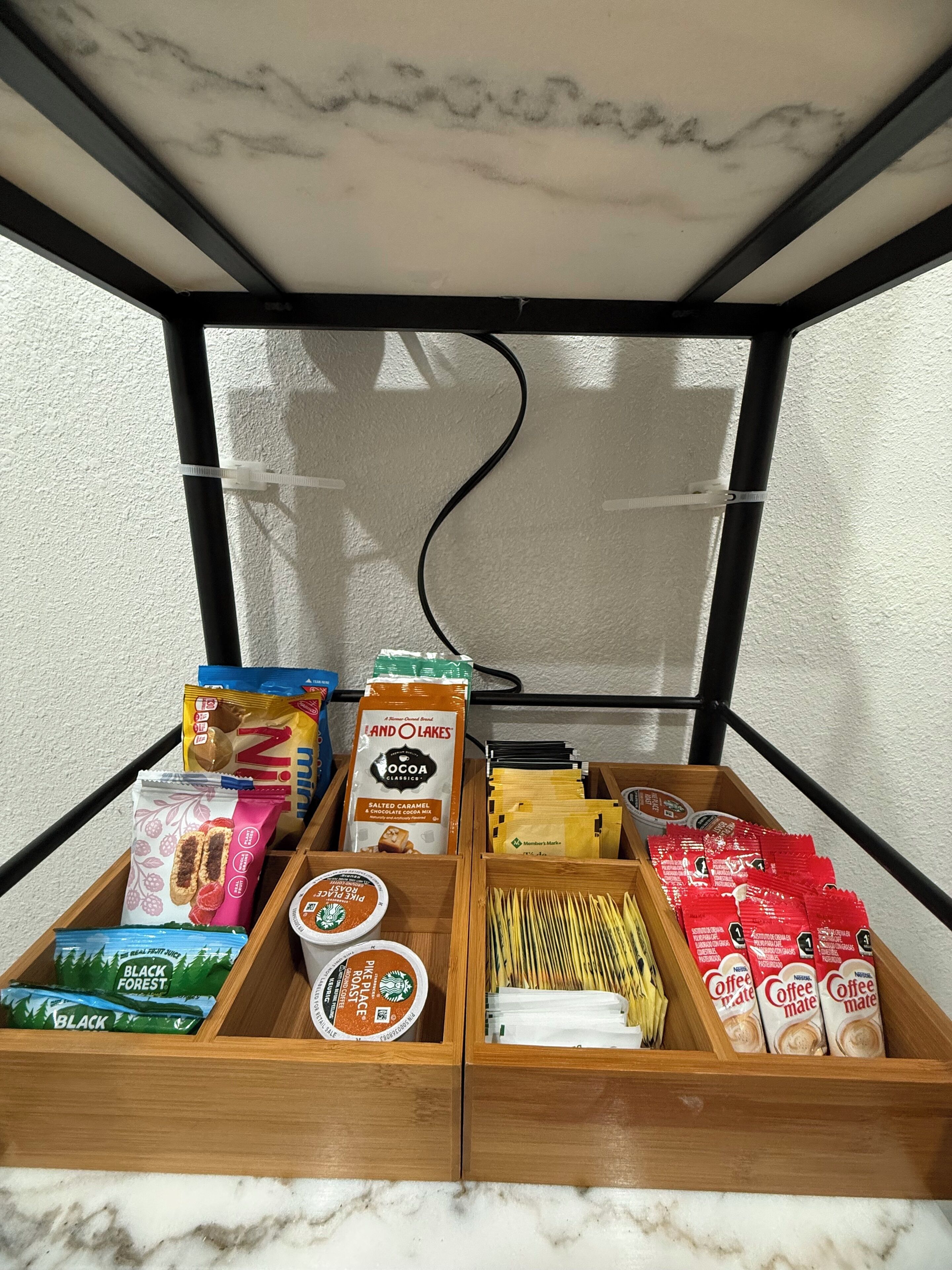 A wooden display case with various food items including snacks, coffee, and tea.