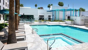 Une piscine avec des chaises longues et des palmiers.