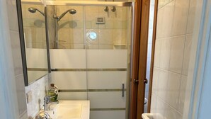 Ein Badezimmer mit Dusche, Waschbecken, Spiegel und Toilette.