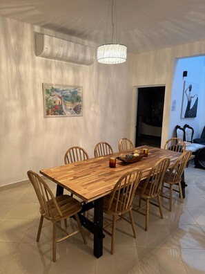 A dining area with a wooden table and chairs, a chandelier, and artwork on the walls.