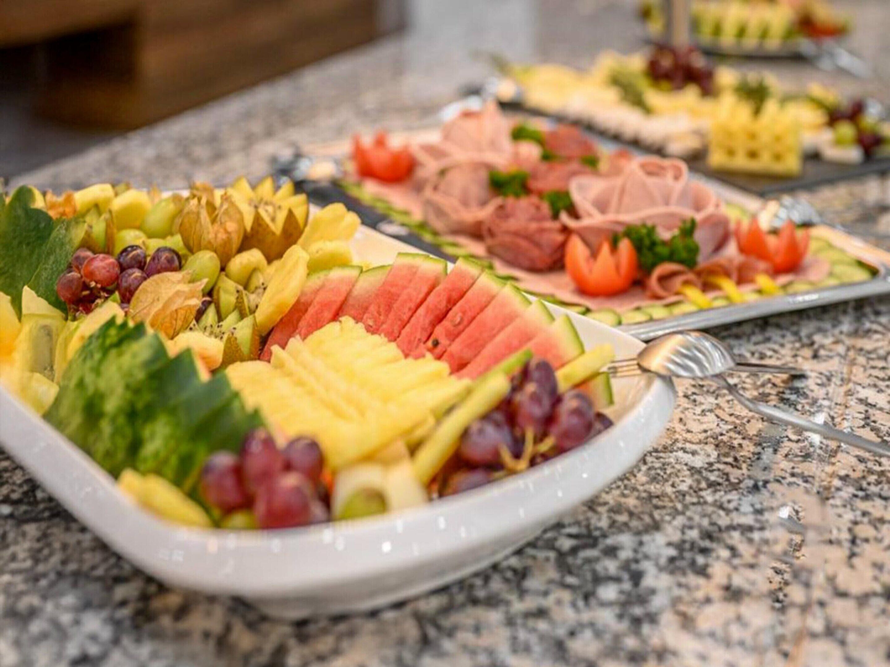 A buffet table with various fruits and meats.