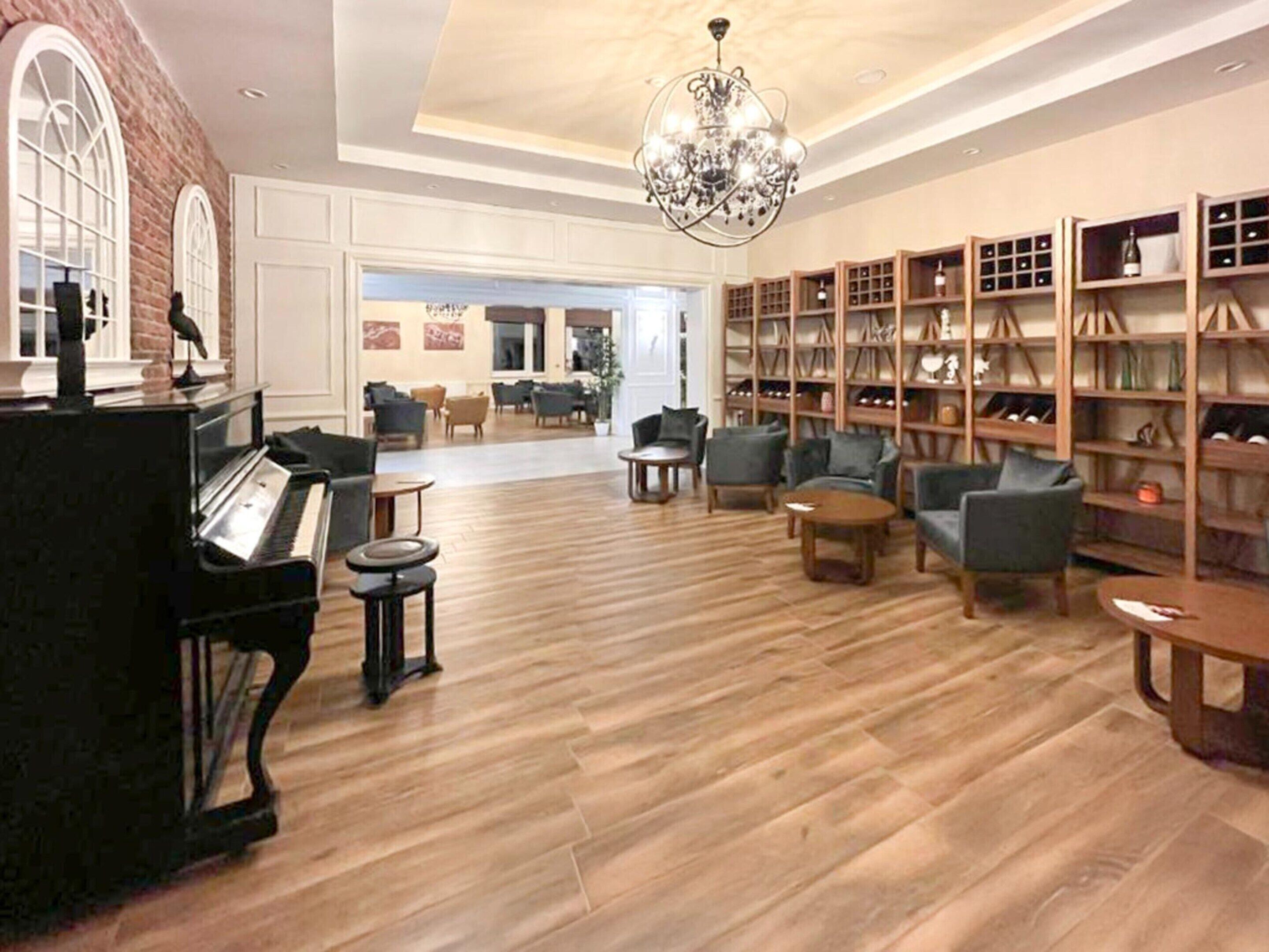 A spacious lobby with a grand piano, comfortable seating, and a wine cellar.