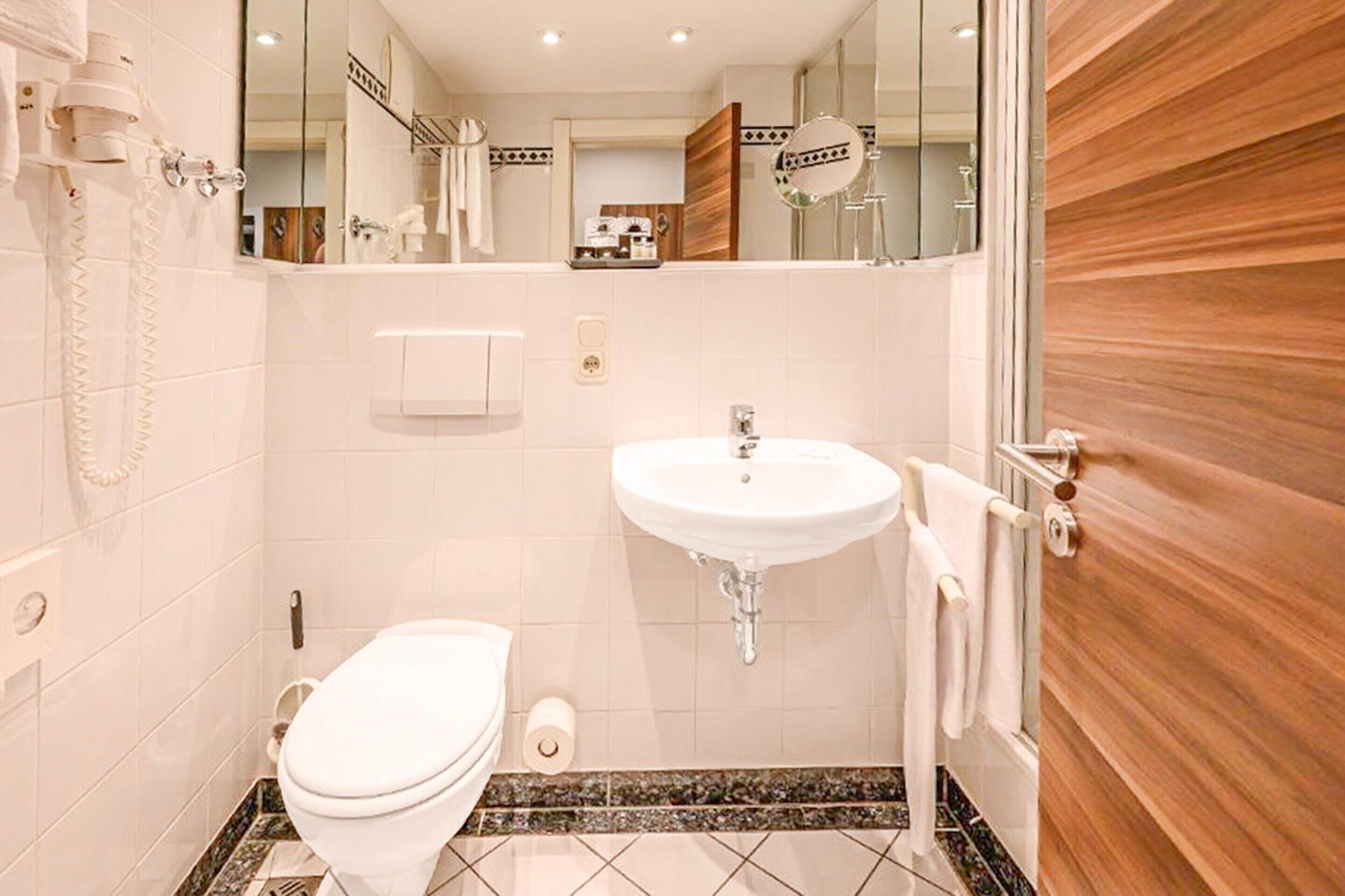 A modern bathroom with a white toilet, a sink, and a mirror.