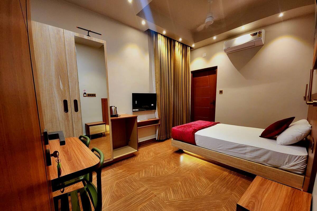 A compact hotel room with a bed, a desk, a television, and a wardrobe.