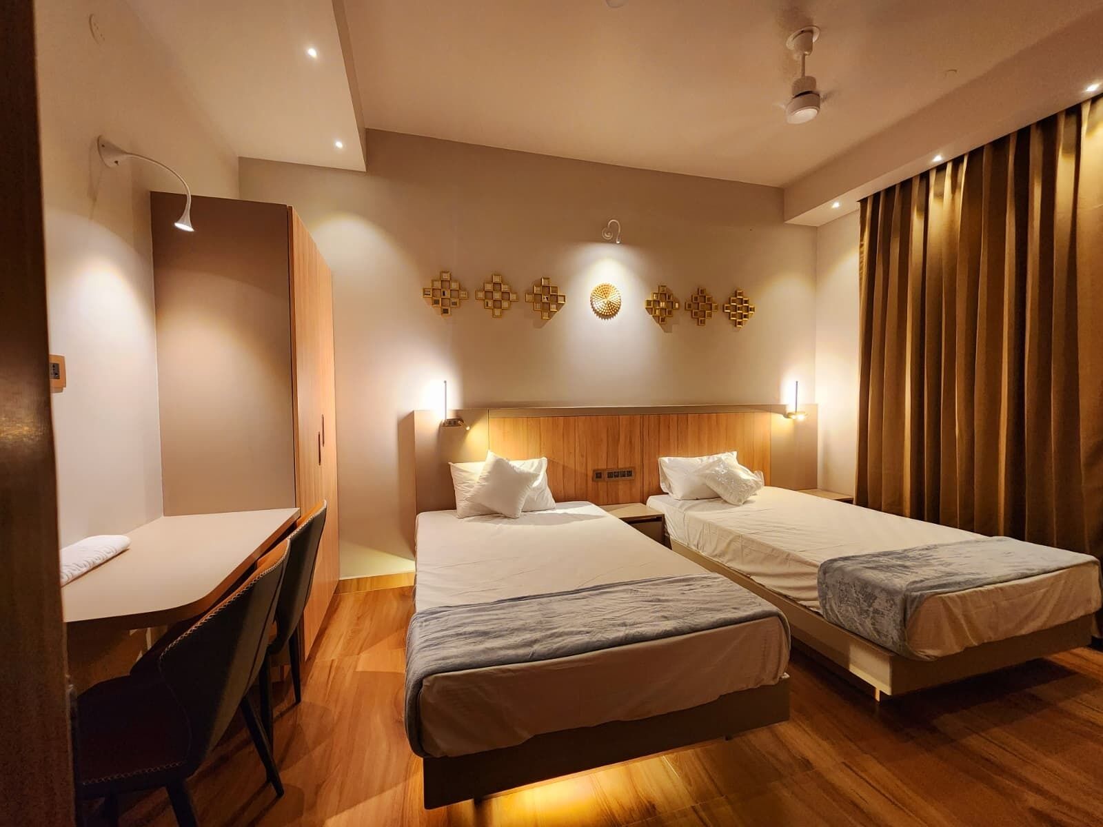 A hotel room with two beds, a desk, and a chair.