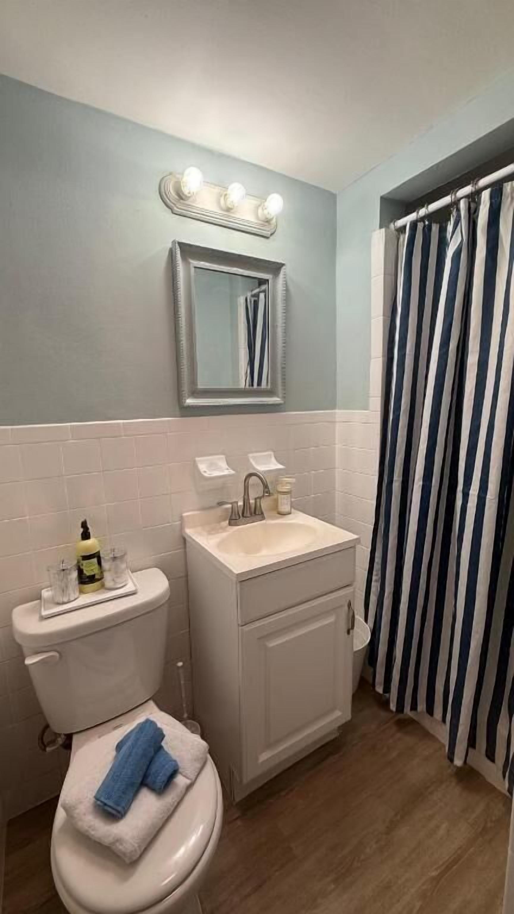A bathroom with a toilet, sink, vanity, and a shower curtain.