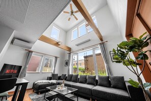 A modern living room with a sectional sofa, a coffee table, a TV, and a ceiling fan.
