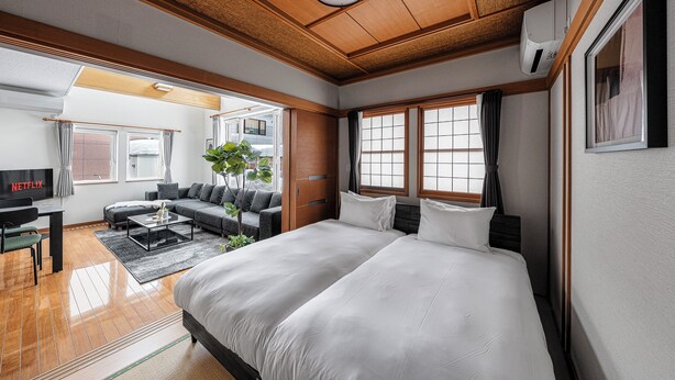 A modern hotel room with a large bed, a sofa, a coffee table, and a TV.