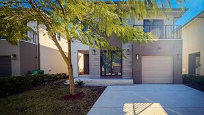 A modern two-story house with a covered driveway, a garage, and a well-maintained lawn. - Serenity Retreat Wellness Club Yoga Cold Plunge (Florida City)
