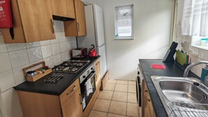 Una cocina con gabinetes de madera, estufa a gas, tostadora y un lavamanos.