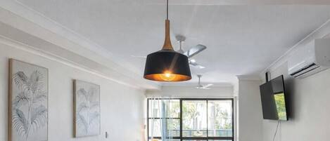 Una sala moderna con sofá, una mesa de centro, una lámpara colgante y una cama con vistas al exterior.